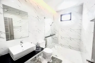 Sleek modern bathroom with marble tiles, glass shower, and stylish fixtures, perfect for a contemporary home.
