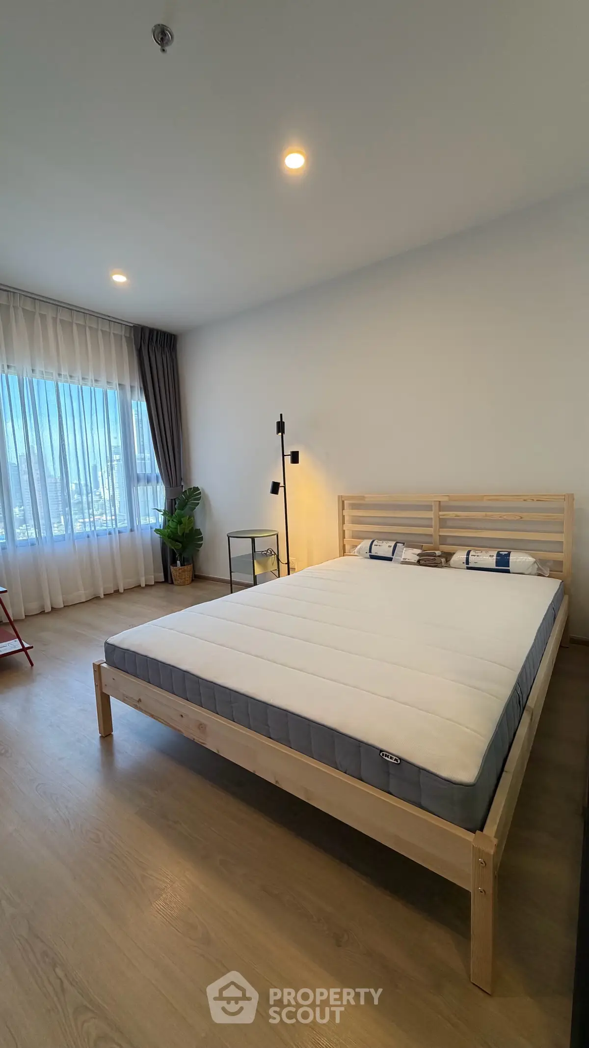 Spacious bedroom with modern decor and large window offering natural light.