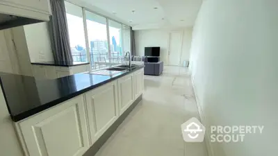 Spacious open-plan living room with modern kitchen and city view, ideal for urban living.