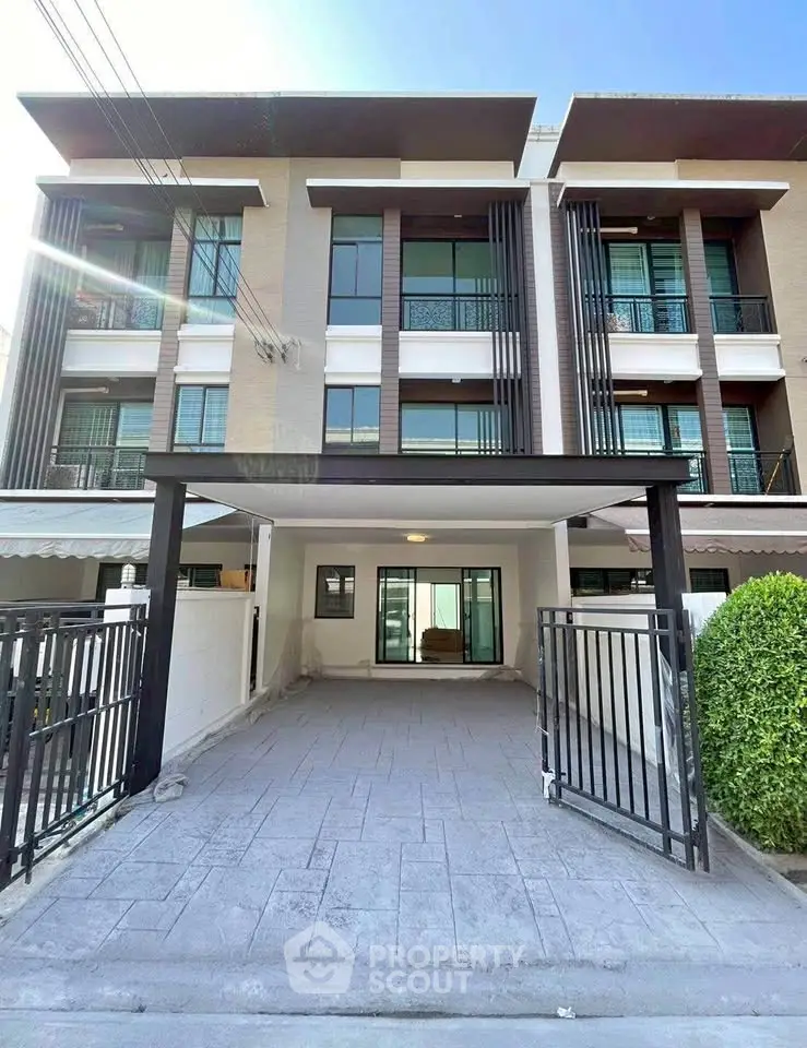 Modern three-story townhouse with gated driveway and contemporary facade.
