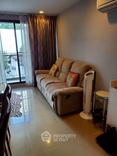 Cozy living room with plush sofa and balcony view, perfect for relaxation.