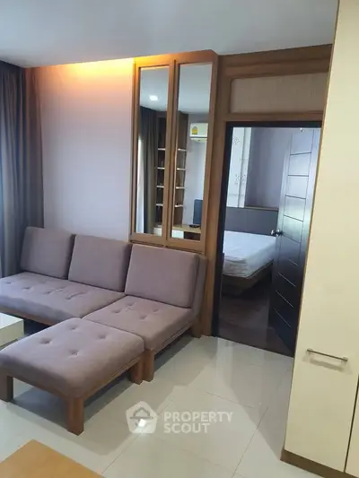 Modern living room with cozy sofa and view into a stylish bedroom