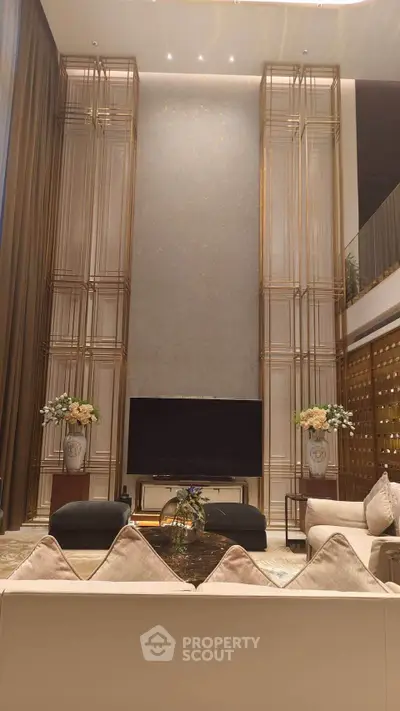 Luxurious living room with high ceilings and elegant decor, featuring a large TV and stylish furniture.