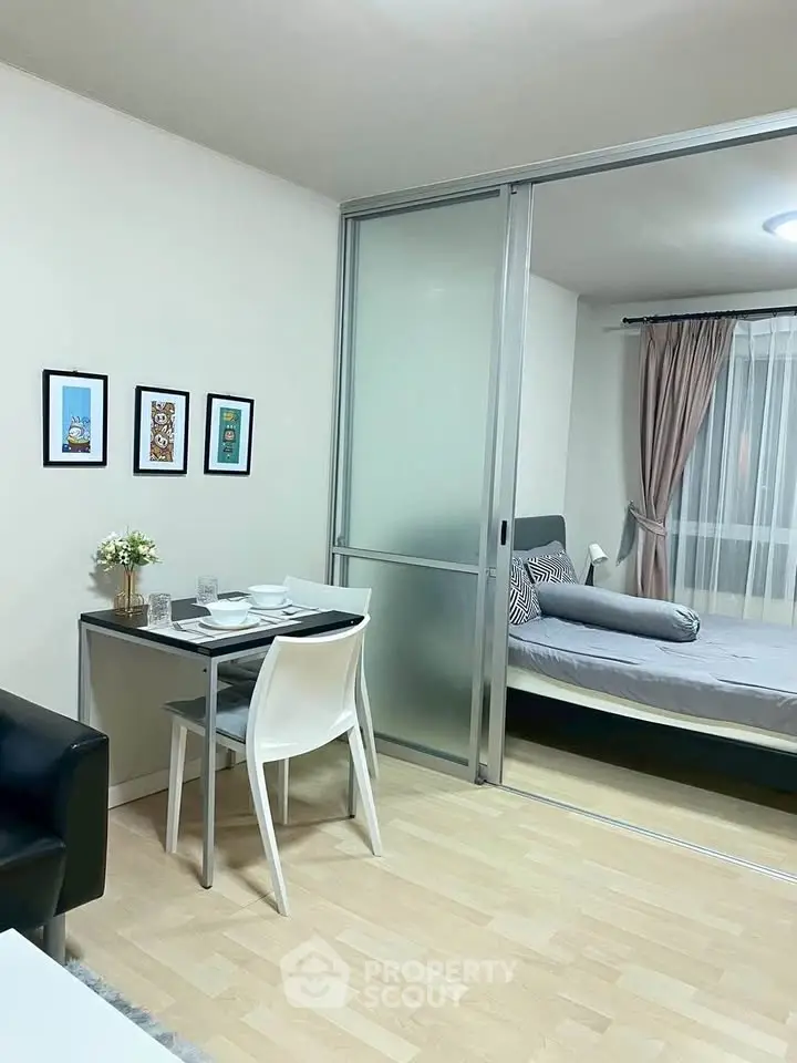 Modern studio apartment with sliding glass partition and cozy dining area.