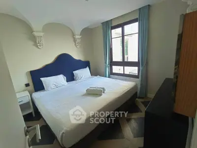 Elegant bedroom with large window and stylish decor, perfect for relaxation and comfort.