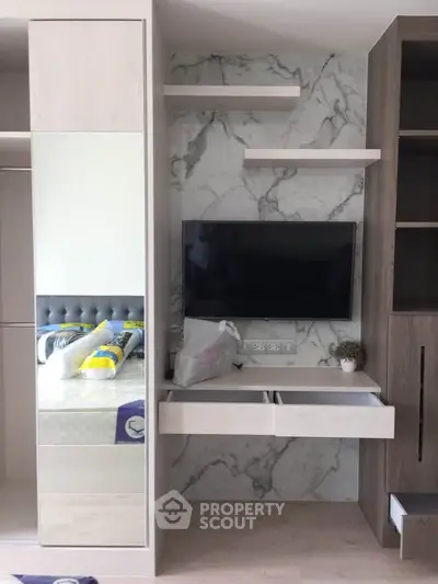 Modern bedroom with built-in wardrobe and mounted TV on marble accent wall.