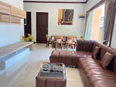 Spacious living room with modern leather sofa and dining area, featuring elegant decor and natural light.