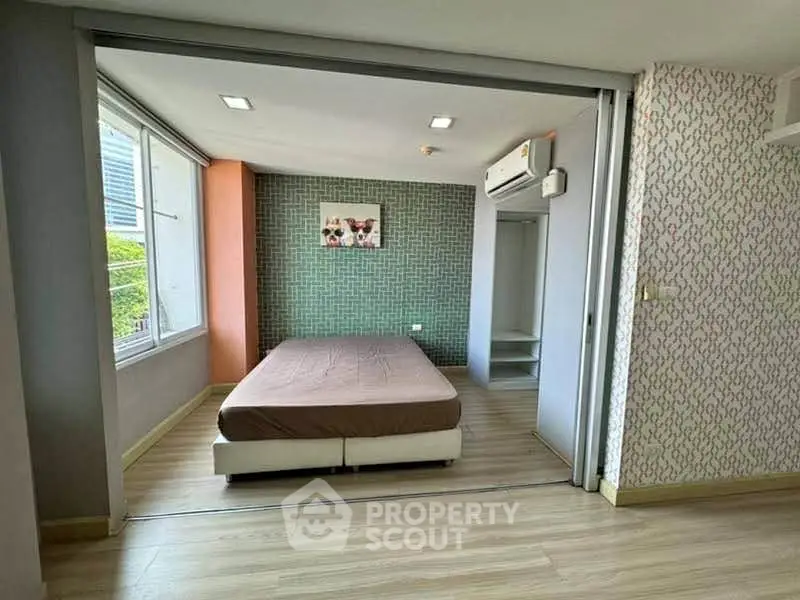 Spacious bedroom with modern decor and large windows for natural light.