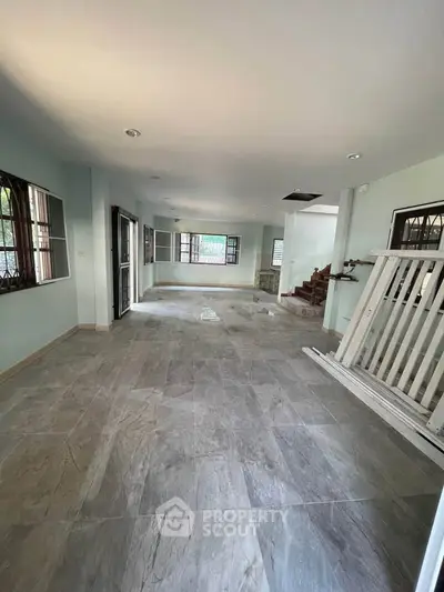Spacious open-plan living area with tiled flooring and ample natural light.