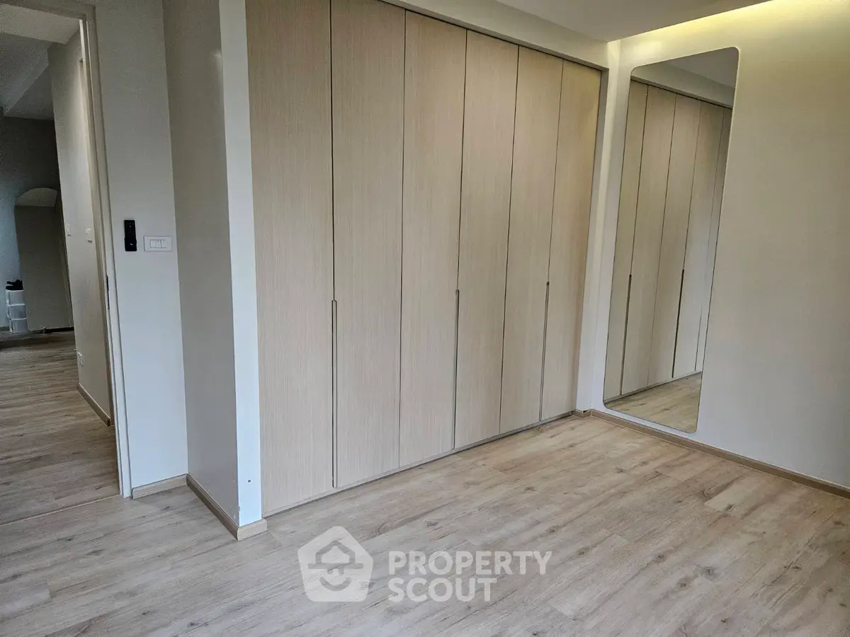 Spacious modern bedroom with sleek built-in wardrobes and elegant wooden flooring.