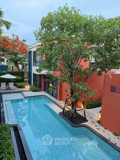 Luxurious residential pool area with lush greenery and modern architecture.
