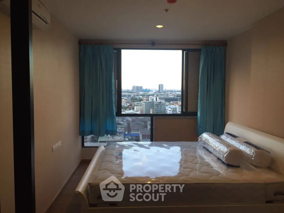 Modern bedroom with city view and large window, featuring a comfortable bed and stylish decor.