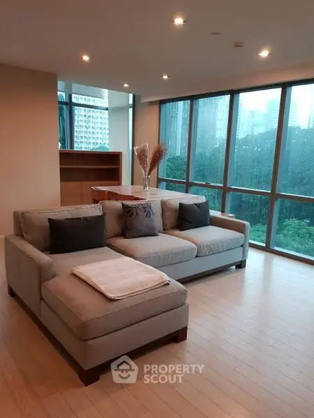 Spacious living room with large windows and modern furniture in a high-rise apartment.