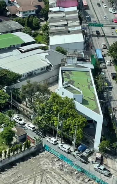 Aerial view of modern building with unique architecture and green rooftop in urban setting.