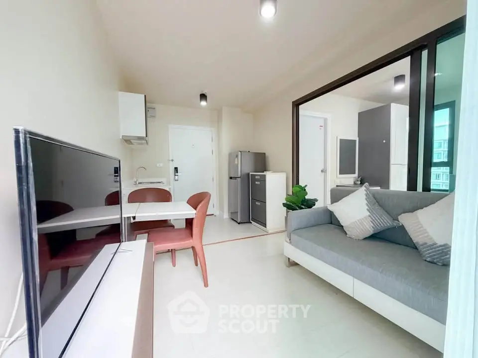 Modern living room with open layout, cozy sofa, dining area, and sleek kitchen appliances.