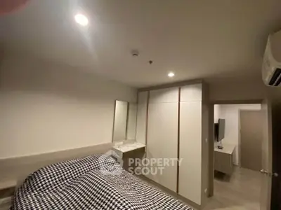 Modern bedroom with stylish checkered bedding and built-in wardrobe in a cozy apartment.