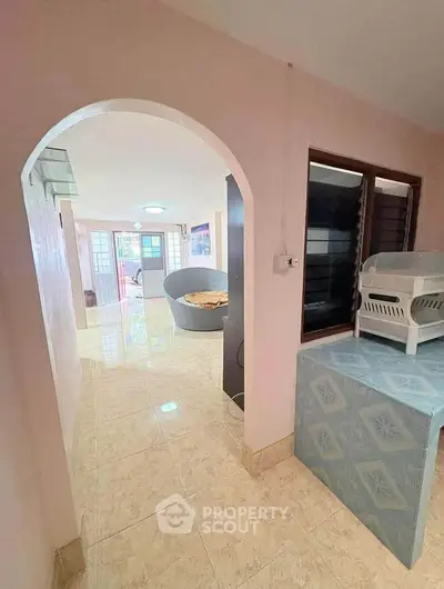 Spacious living area with tiled flooring and archway entrance, featuring modern furniture and natural light.