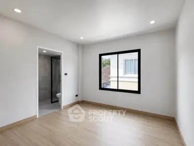 Spacious empty room with large window and adjacent bathroom, perfect for customization.