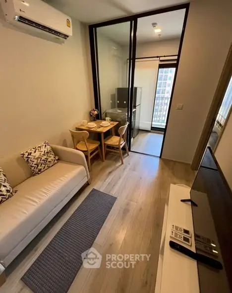 Modern living room with cozy sofa, dining area, and balcony view in a stylish apartment.