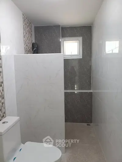 Modern bathroom with sleek tile design and natural light window.