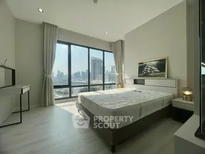 Spacious bedroom with large windows offering stunning city views, modern furnishings, and natural light.