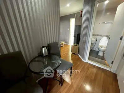 Cozy apartment interior with modern decor and wooden flooring, featuring a small dining area and bathroom access.