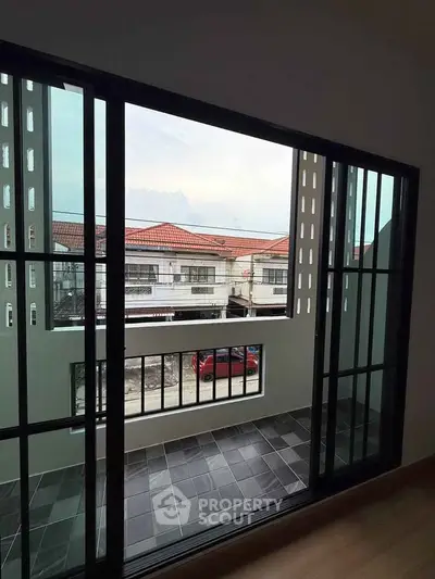 Modern balcony with sliding glass doors and tiled floor overlooking residential area.