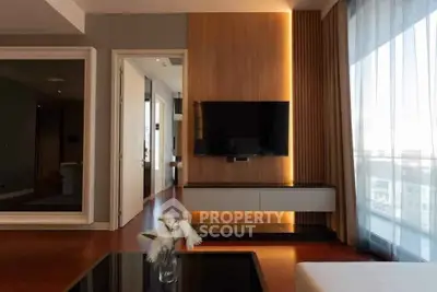 Modern living room with sleek TV setup and large window for natural light.