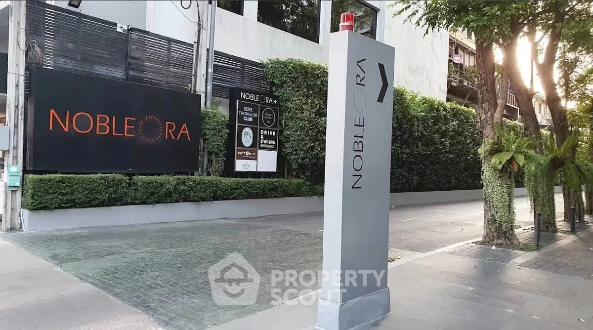 Modern entrance of Noble Ora with sleek signage and lush greenery.