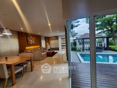 Luxurious open-plan living room with pool view, modern furnishings, and elegant lighting.