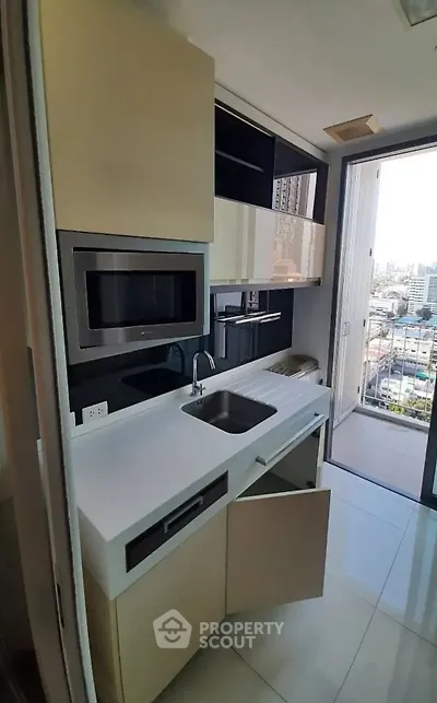 Modern kitchen with sleek cabinetry and city view from balcony.