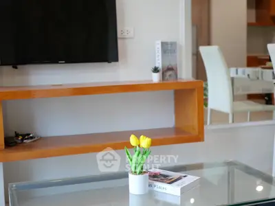 Modern living room with sleek glass table and wooden shelf, featuring a TV and stylish decor.