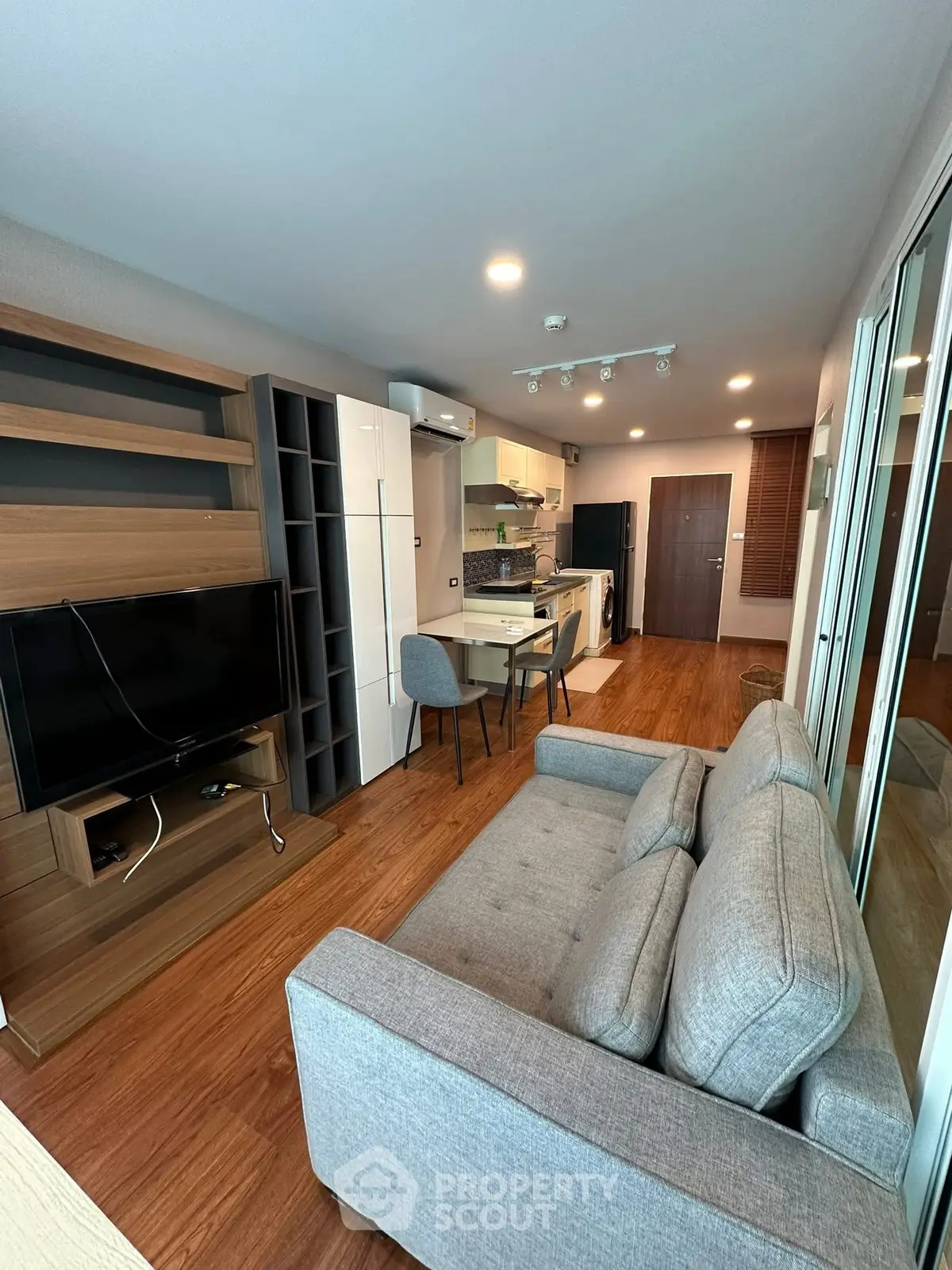 Modern open-plan living room with kitchen, featuring sleek furniture and wooden flooring.