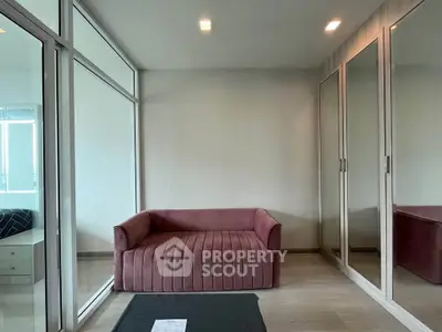 Modern living room with stylish pink sofa and mirrored wardrobe in a bright apartment.