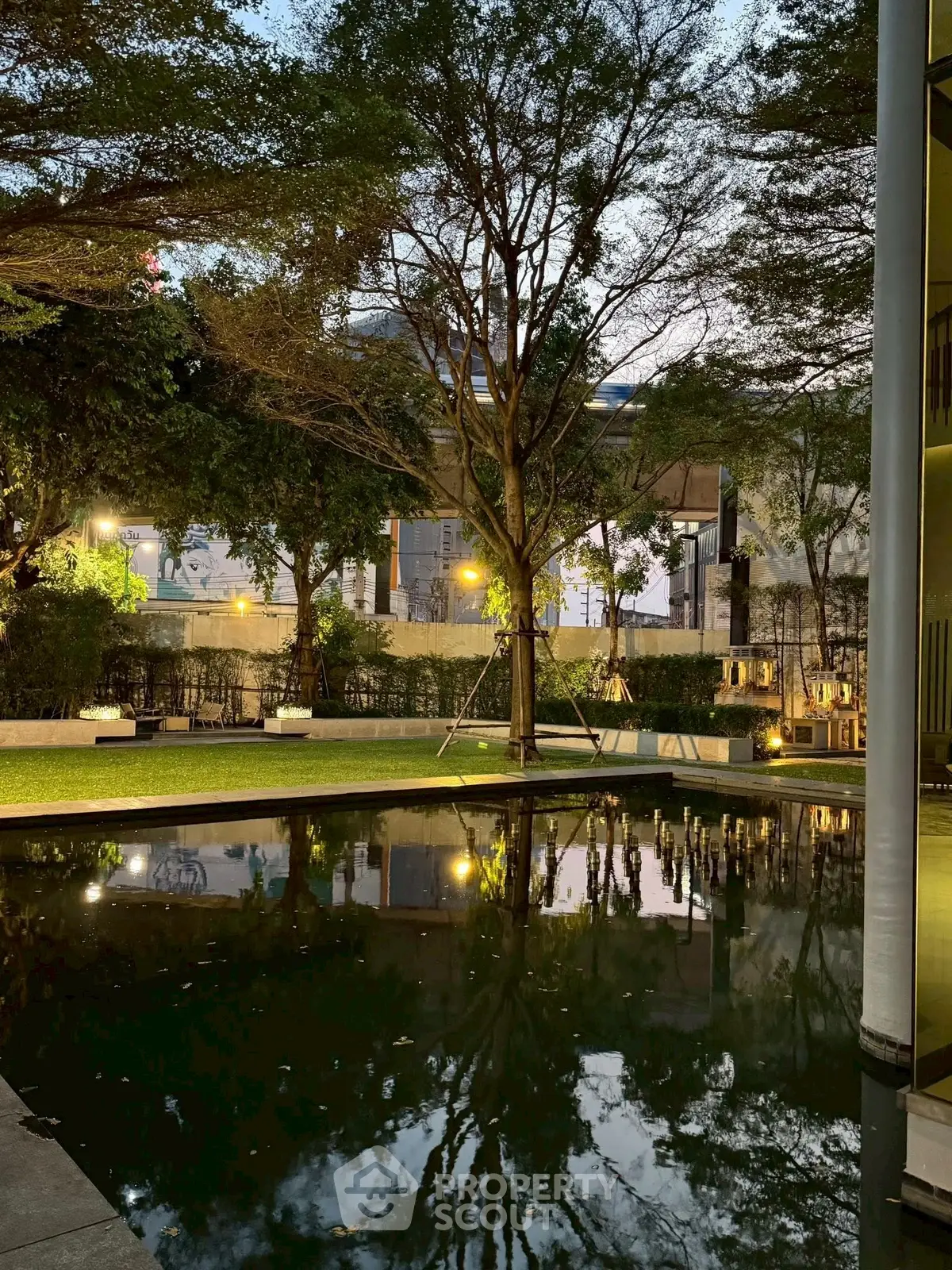 Serene garden view with reflective pond and lush trees at dusk