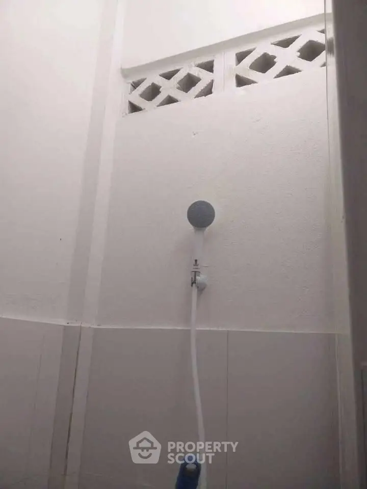 Minimalist bathroom with white walls and shower head, simple and clean design.