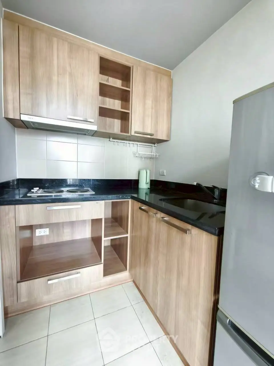 Modern compact kitchen with wooden cabinets and black countertops in a cozy apartment.