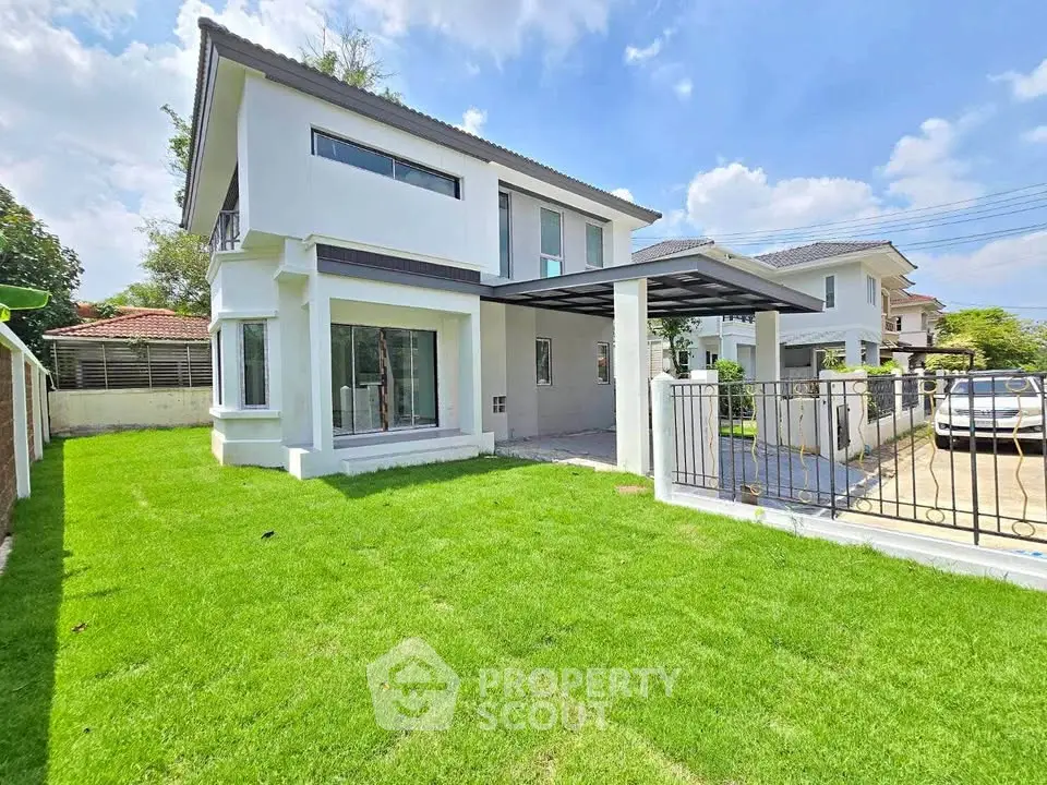 Modern two-story house with spacious green lawn and gated driveway in a serene neighborhood.