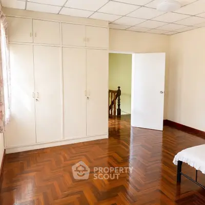 Spacious bedroom with wooden flooring and built-in wardrobe, perfect for cozy living.