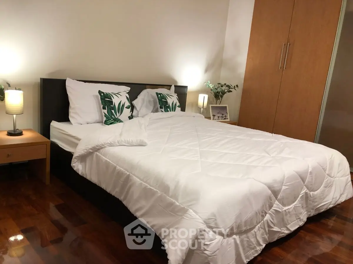 Cozy bedroom with wooden flooring and modern decor, featuring a comfortable bed and stylish lighting.