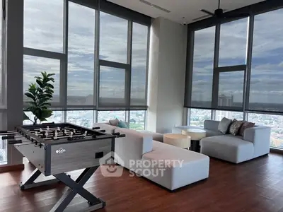 Spacious modern living room with panoramic city views and foosball table.