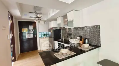 Modern kitchen with sleek black countertops and stylish backsplash in a cozy apartment.