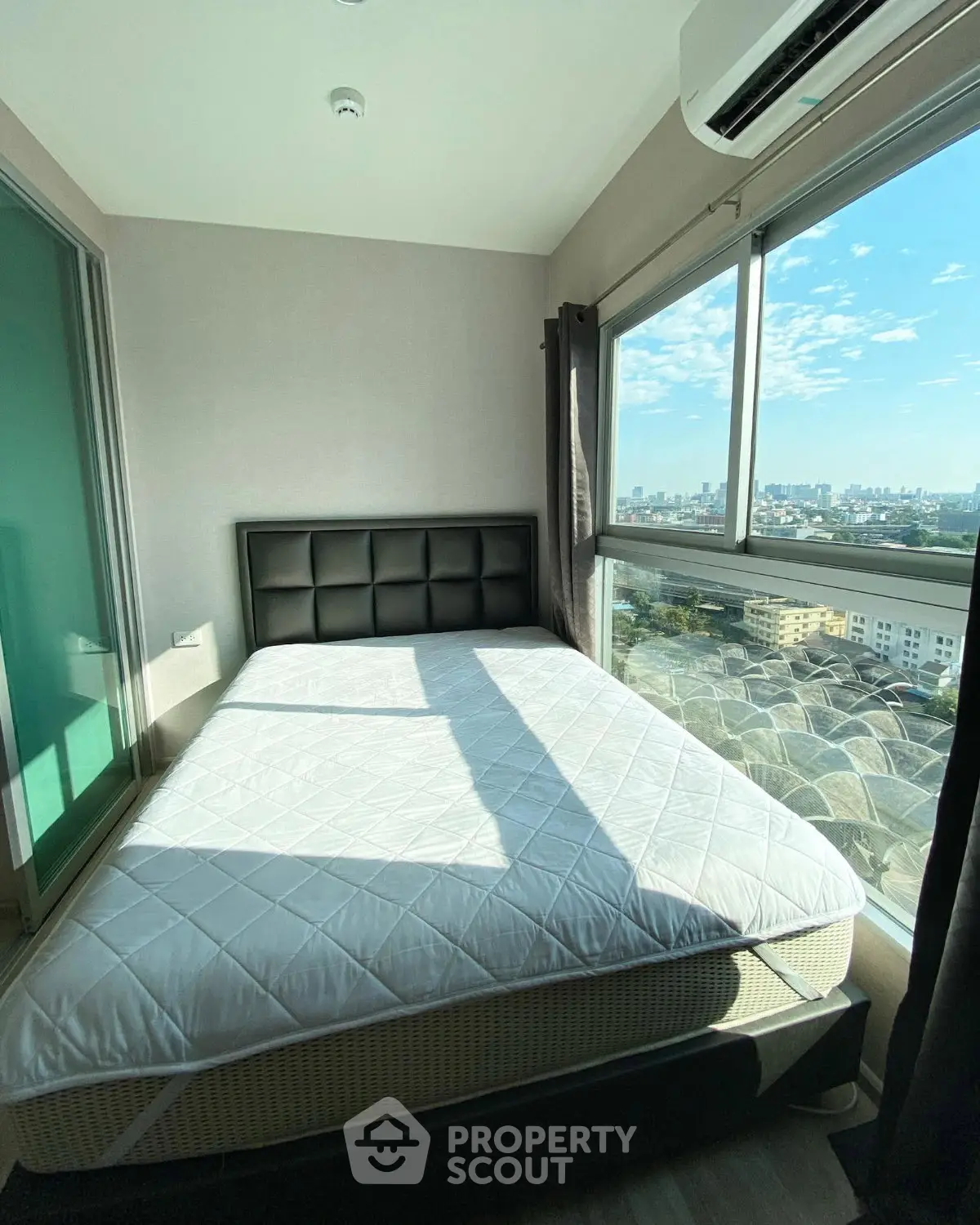 Bright bedroom with large window offering stunning city views and modern furnishings.
