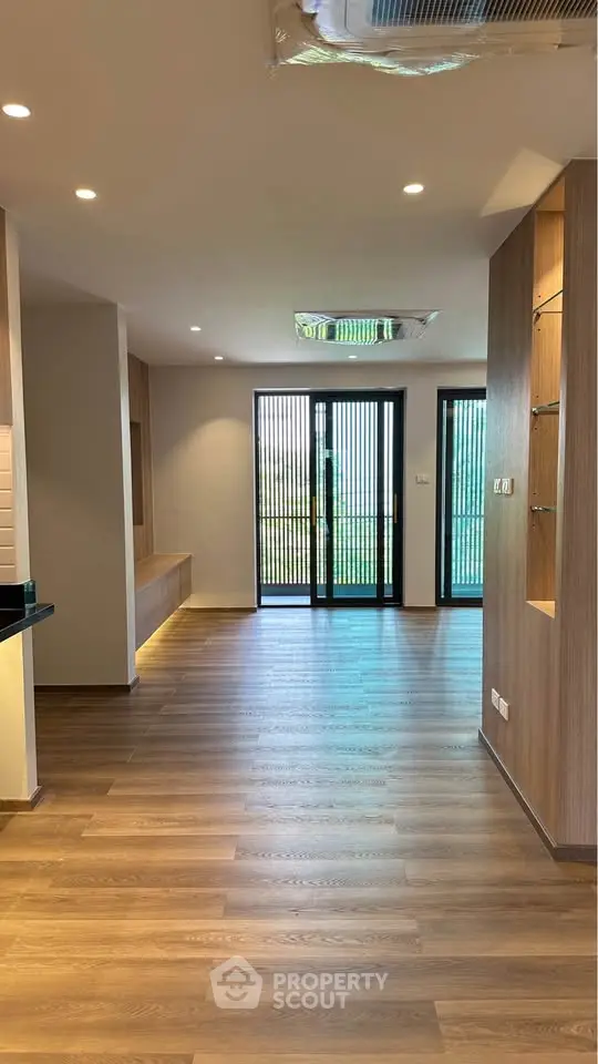 Spacious modern living room with wooden flooring and large glass doors leading to a garden view.