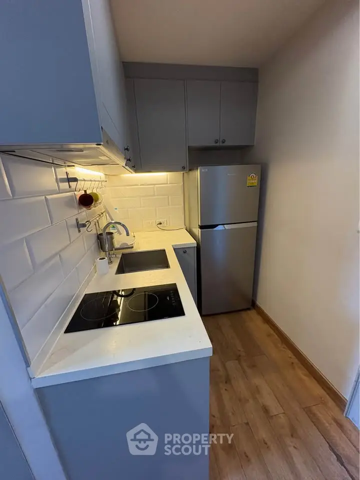 Modern compact kitchen with sleek cabinetry and built-in appliances in a cozy apartment.