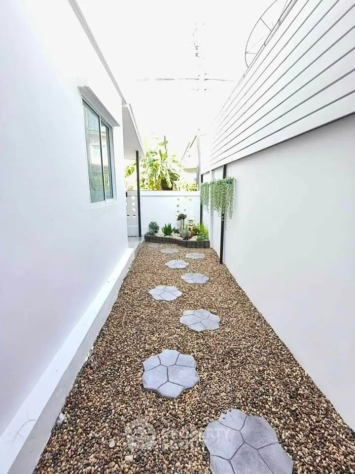 Charming narrow garden path with stepping stones and modern white walls