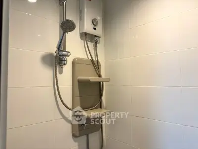 Modern bathroom shower with sleek white tiles and efficient water heater.