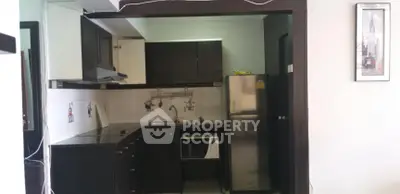 Compact kitchen with dark cabinets and stainless steel appliances in modern apartment.