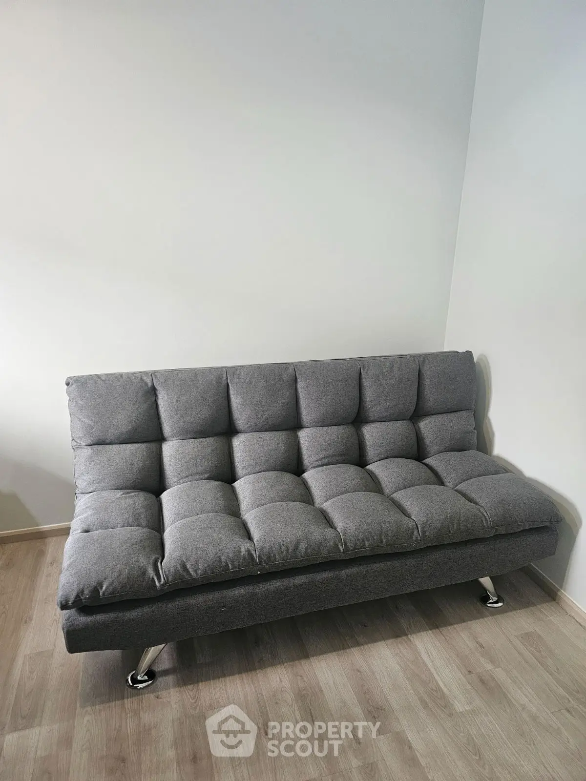 Modern gray sofa in a minimalist living room with wooden flooring.