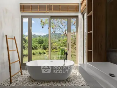 Luxurious bathroom with freestanding tub and scenic nature view through large windows.